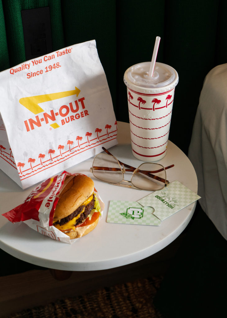 Palihotel Hollywood - Side table with In-N-Out Burger bag, hamburger, and shake. Also sunglasses and hotel room key card.
