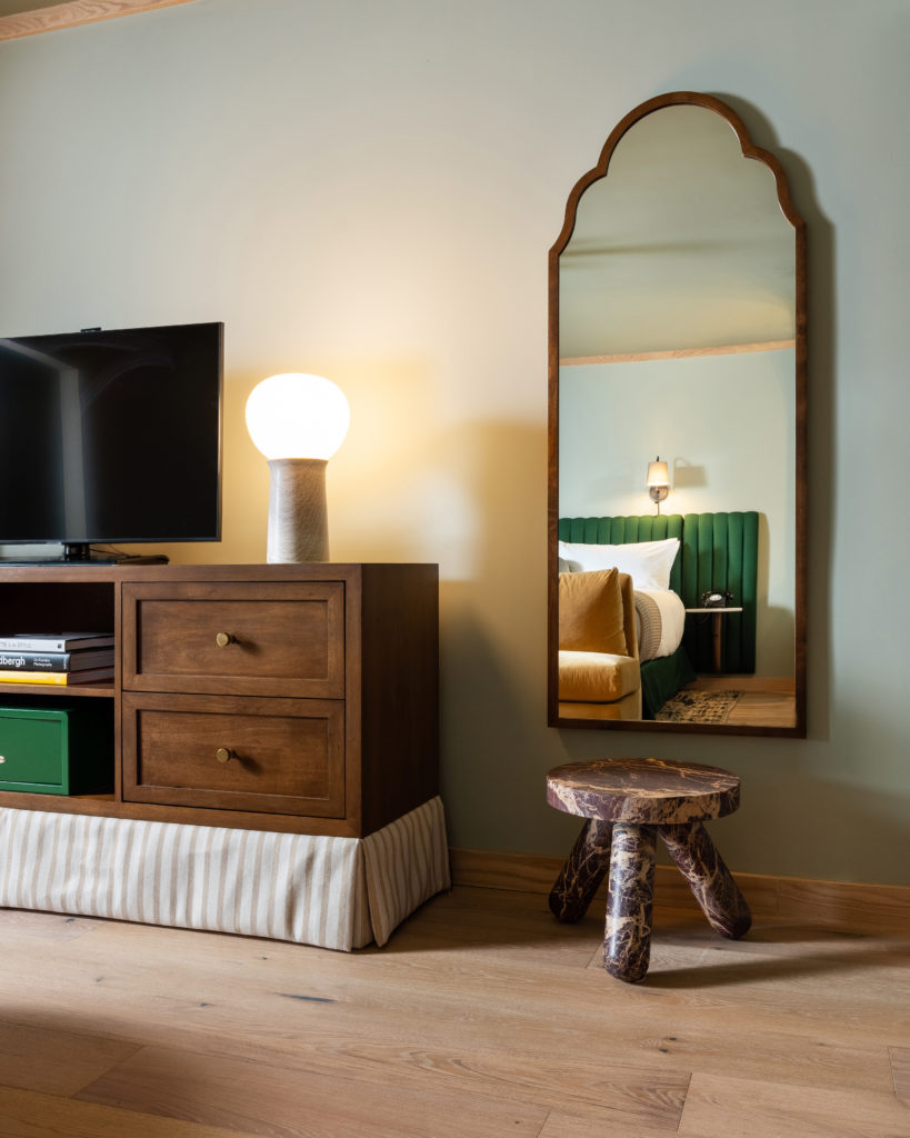 Palihotel Hollywood - credenza with television and lamp on top, small stool under decorative mirror