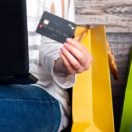 Woman sitting with laptop and colorful gift bags shopping online