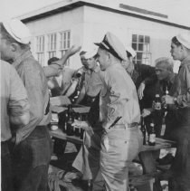 sailors standing around a picnic table with beers