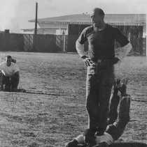 Vince Olivera, UDT instructor circa 1962 stands on back of trainee