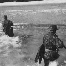 sailors walking into the surf with weapons