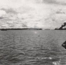 Sailor watching ship burn in the distance