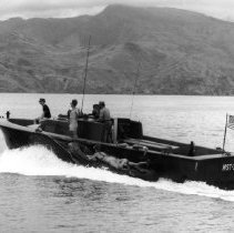 two swimmers lie on an inflatable boat being towed by a utility boat.