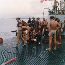SEALs in swim trunks on deck of a ship