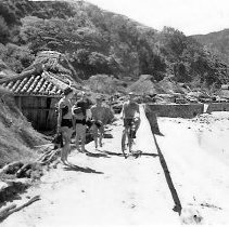 Men On Beach With Fins, One On A Bicycle