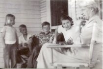 Children sitting with Ide Heitzman on her porch