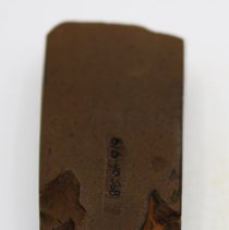 Lengthwise view of polished side of basalt adze with alternate id # visible
