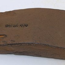 Polished side of basalt adze fragment with alternate id number visible