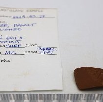 Polished basalt adze with artifact slip and ruler