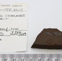 Basalt adze fragment with artifact clip and ruler