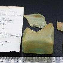 Fragments of glass bottle with artifact slip and ruler