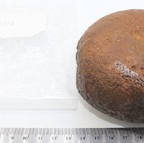 Basalt hammerstone with artifact bag and ruler