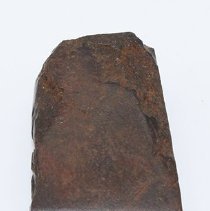 Lengthwise view of small basalt adze with ruler