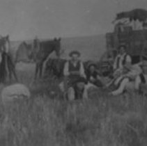 Cowboys resing by wagon.