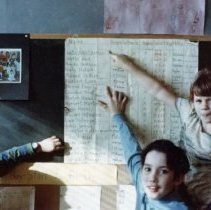 Color, 3.5x5. Students pointing to their names on a chart. "That's my name!"