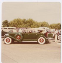 Green bodied Packard convertible with spectators around