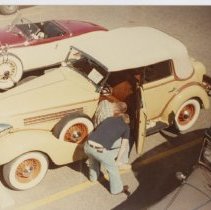 2 unidentified men Looking at the interior of a yellow Auburn