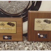 Two Plaques on the ground in front of a tire both won by Larry Hendricks