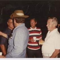 Group of four unidentified men chat with drinks in their hand