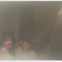 Two unidentified men talk in bottom left, inside, light glare