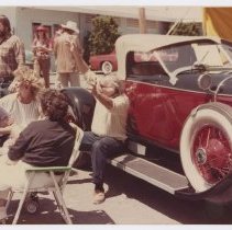 Group of four unidentified poeple sitting to the side of a 1928 or 1929 Auburn speedster