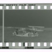 Cord L-29 Cabriolet in front of Stinson airplane out in field.