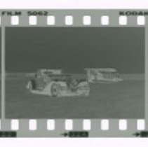 Cord L-29 Cabriolet in front of Stinson airplane out in field.