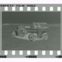 Cord L-29 Cabriolet in front of Stinson airplane out in field.