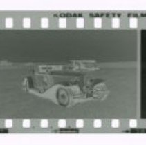 Cord L-29 Cabriolet in front of Stinson airplane out in field.