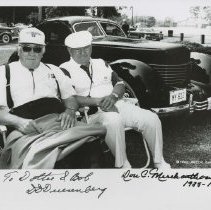 Black and white image of duo lazing in front of Cord 810-812 Sedan on grass. License plate number "My 812."