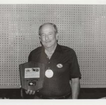 Black and white photo of a Robert Russell holding an ACD Club award plaque for Primary First Place