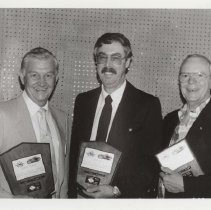 Black and white photo of three ACD Club members holding award plaques