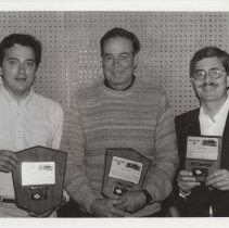 Black and white photo of three ACD Club members holding award plaques