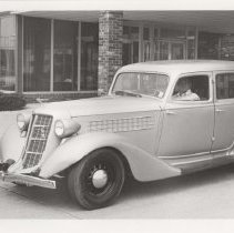 Black and white photo of a man driving a 1936 Auburn 654 sedan