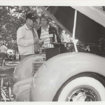 Black and white photo of two unidentified men through the open hood of a Cord 810 or 812