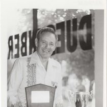 Black and white photo of an unidentified man with his award plaque and trophy