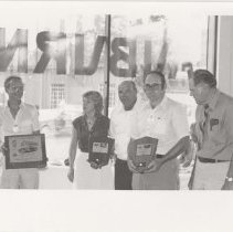 Five people, three holding award plaques
