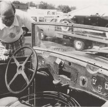 Black and white photo of Robert Joynt looking at the rusted dash of a Cord L-29