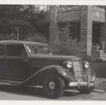 1936 Auburn 654 brougham in front of a brick building