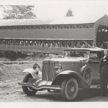 Couple next to a 1931 Auburn cabriolet next to a covered bridge