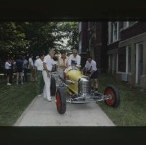 Group pushing Dreyer racecar down sidewalk