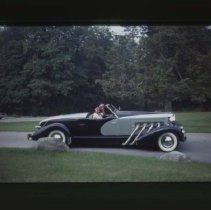 Duesenberg reproduction on road in front of tree line
