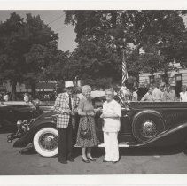 Three people next to Duesenberg Model J-534 in downtown Auburn