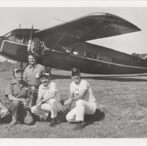 Five men in front of a Stinson