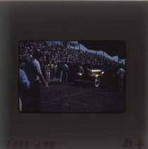 Crowd watching as a golden Packard comes out for auction