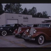 1934 Auburn Phaeton, 1934 Auburn, and 1935 or 1936 Auburn in front of Ester Price Candies