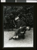 Young boy over man's knee with batton in hand.