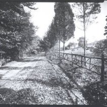 Road with fence looking towards a house and barn