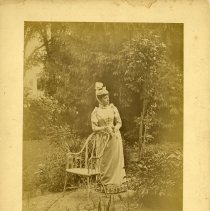 E. Alice Austen, [Alice Austen beside a chair in a garden], ca. 1890